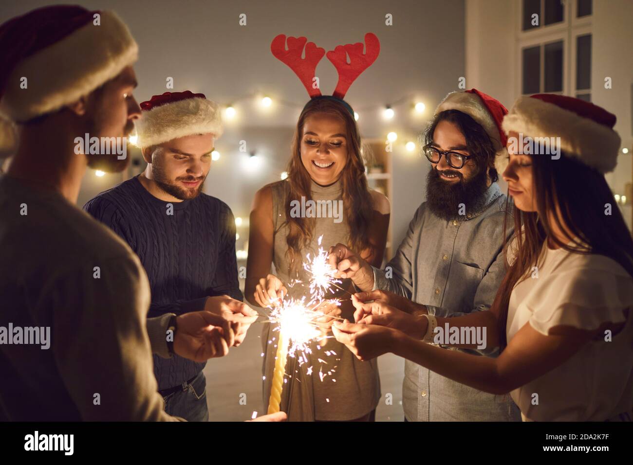 Eine Gruppe junger Freundinnen und Freundinnen stehen in einem Kreis und leuchten am Silvesterabend. Stockfoto