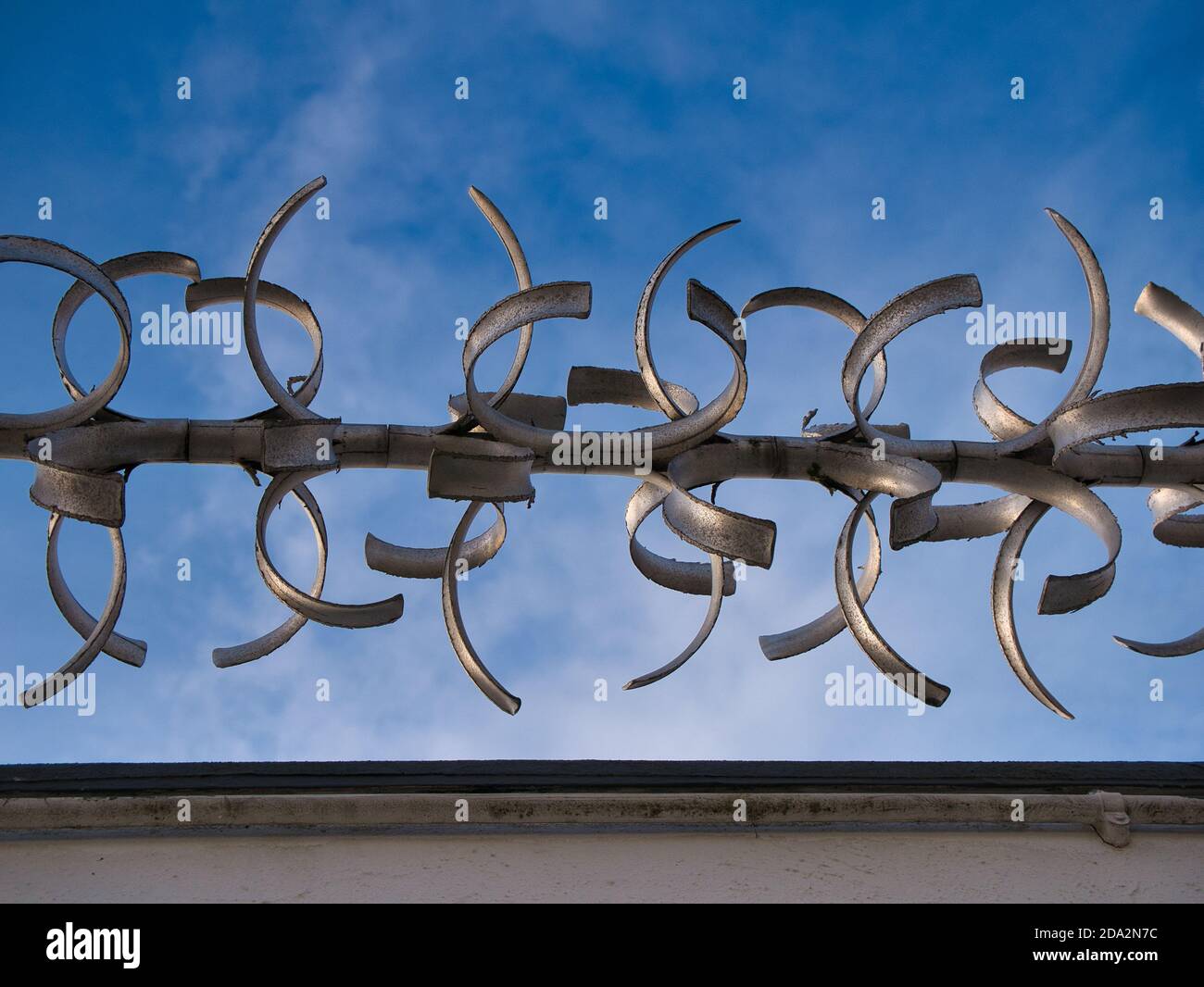 Ein Abschnitt einer rotierenden Wand oben Anti-Climb-Sicherheitsbarriere, gegen einen blauen Himmel an einem sonnigen Tag genommen. Stockfoto