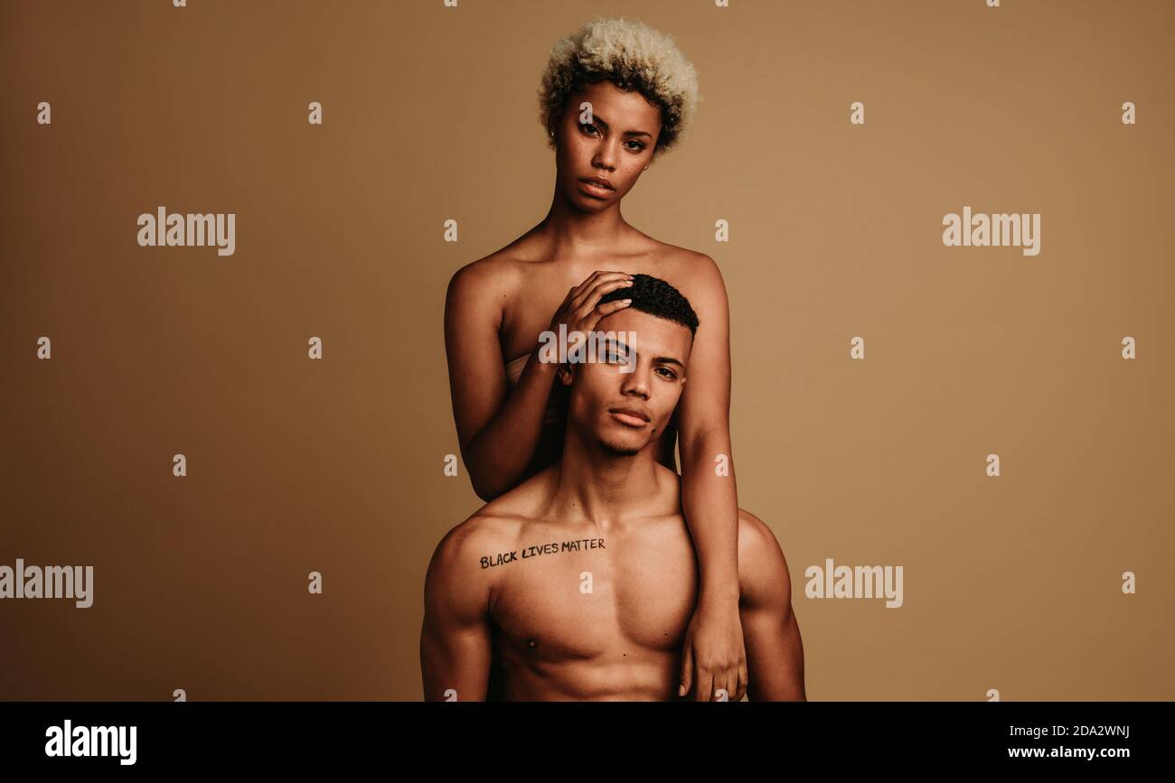 Porträt eines afroamerikanischen Paares, das die Bewegung Black Lives Matter unterstützt. Lockig behaarte Frau hinter muskulösen Mann stehen. Stockfoto