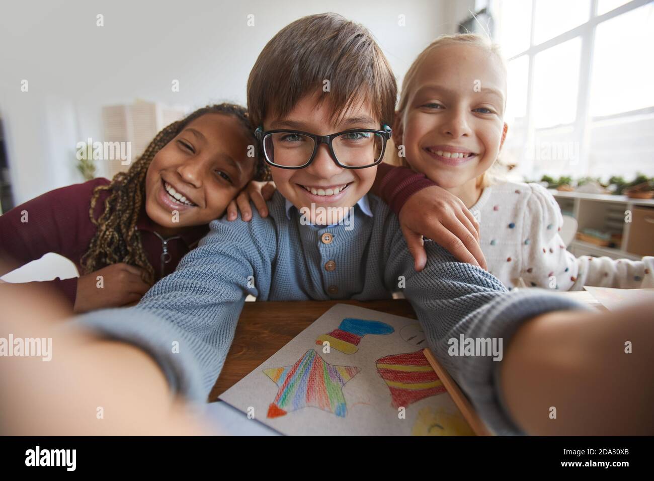 Portrait von drei glücklichen Kindern, die während der Aufnahme die Kamera anlächeln Selfie-Foto in der Schule Stockfoto
