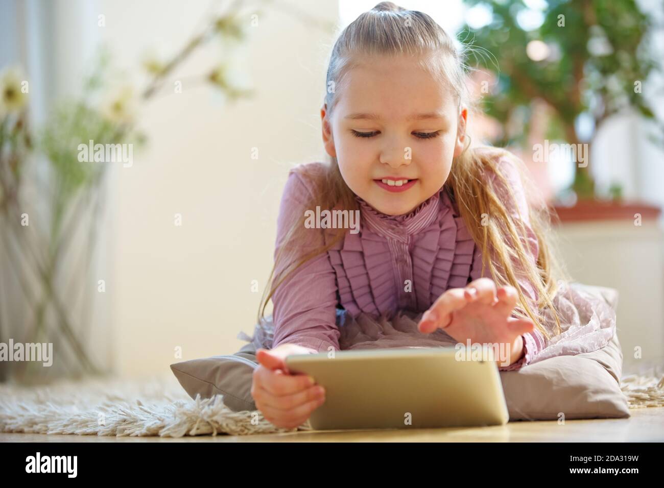 Kind liegt im Wohnzimmer und chattet im Internet Mit einem Tablet-PC Stockfoto