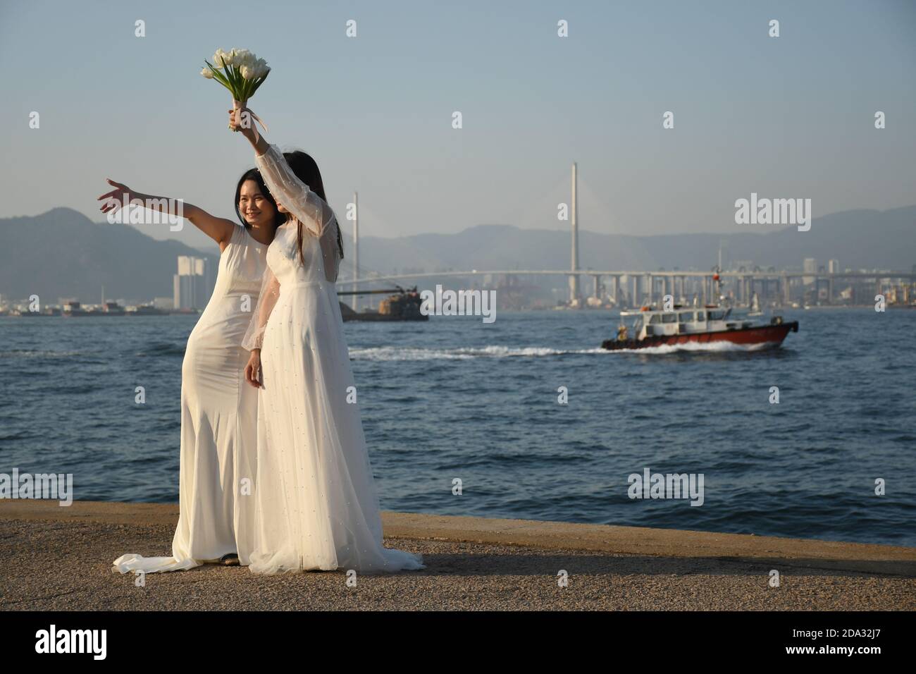 Zwei glückliche Bräute, die im Sai Wan Frachtpier fotografieren (Auch Instagram Pier genannt) in Hongkong Stockfoto