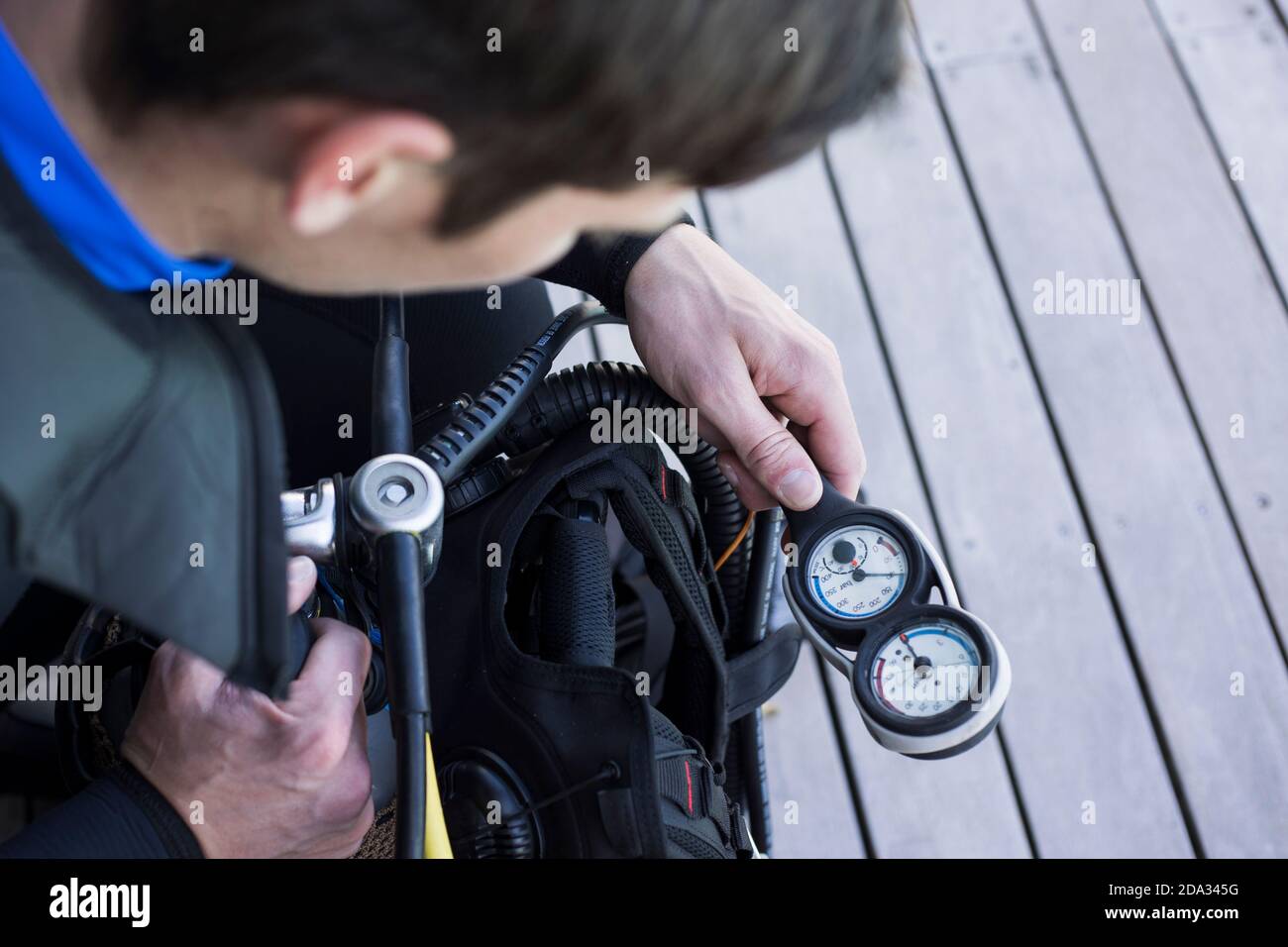 Scuba Diver Kitting und Überprüfung des Manometers, Nahaufnahme der Hand halten Ausrüstung über Schulter Schuss. Stockfoto