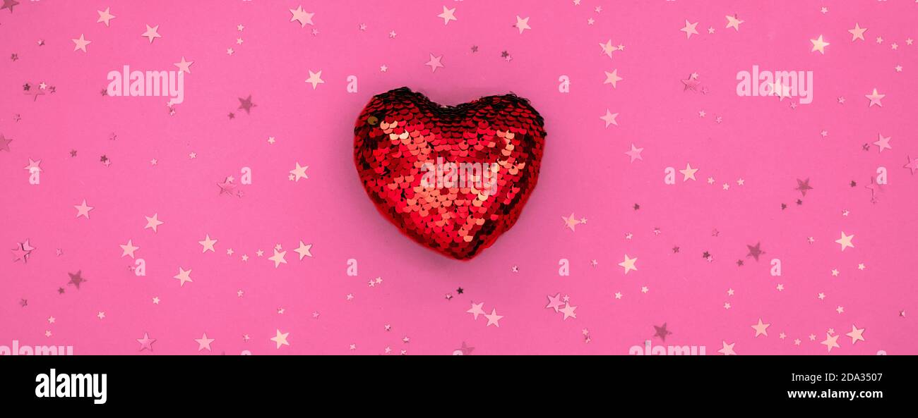 Weihnachts- oder Valentinskomposition aus glühender roter Herzdeko und Glitzer auf rosa Oberfläche. Frohe weihnachten und glückliches Neues Jahr 2021, glücklich Stockfoto