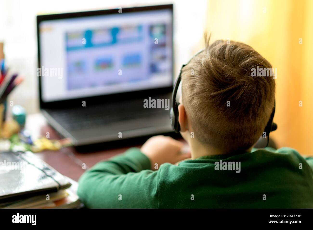 Nahaufnahme EINES verschwommenen selektiven Fokus image.The Junge lernt zu Hause mit Laptop in einer Ferne Fernlernen, Junge verwendet Kopfhörer mit einem Mikrofon. Stockfoto