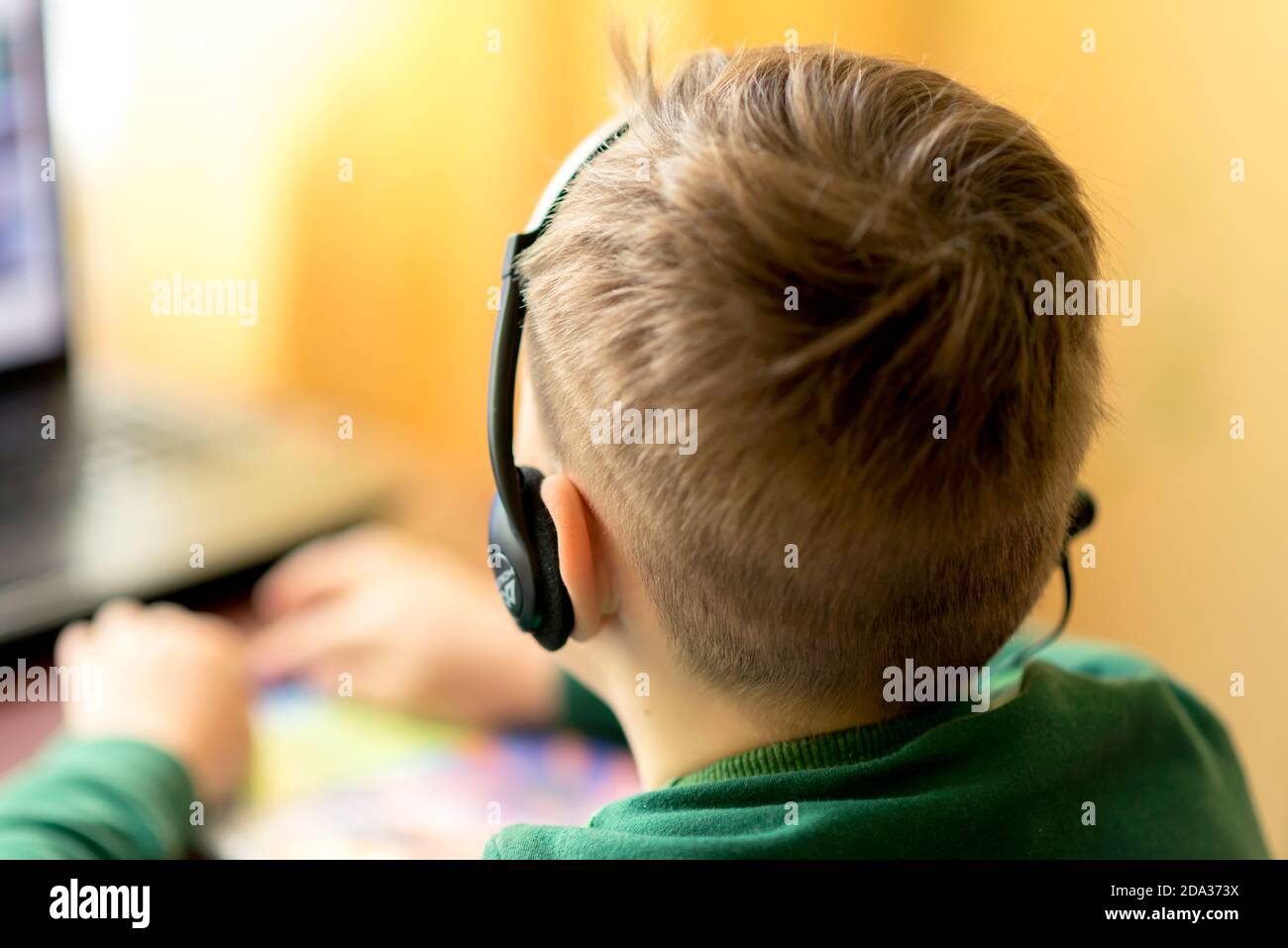 Nahaufnahme EINES verschwommenen selektiven Fokus image.The Junge lernt zu Hause mit Laptop in einer Ferne Fernlernen, Junge verwendet Kopfhörer mit einem Mikrofon. Stockfoto