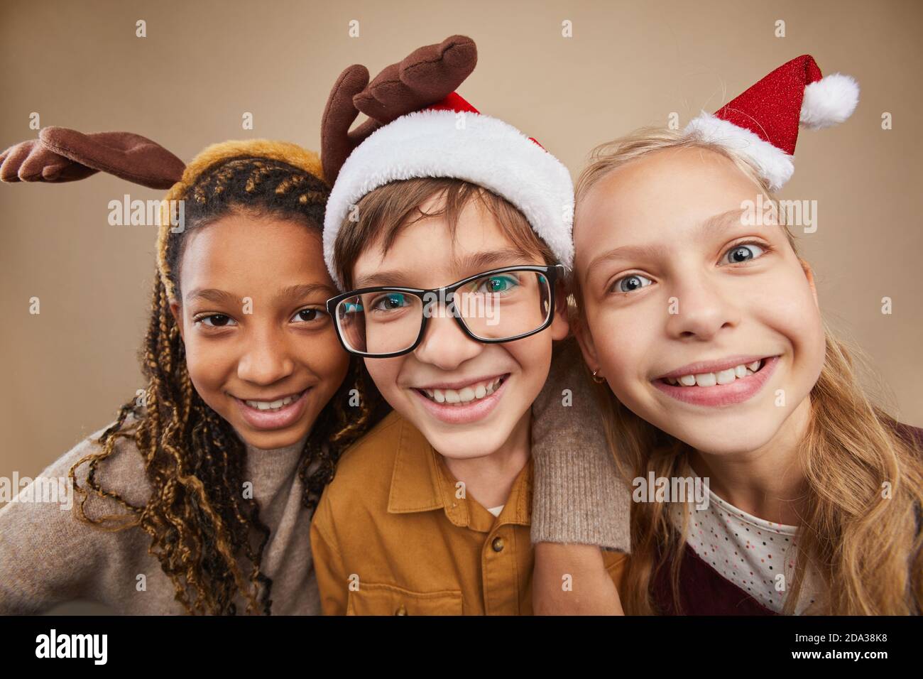 Nahaufnahme Porträt von drei Kindern tragen Weihnachtskostüme und Lächelnd auf die Kamera, während sie im Studio vor dem Hintergrund der Binge steht Stockfoto