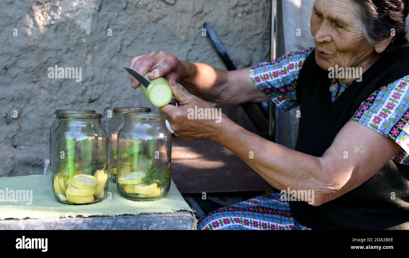 Senior asiatische Frau schneiden und schneiden frischen Squash und in Gläser für hausgemachte Konservierung. Oma bereiten Gemüse als Konservierung in Gläsern Stockfoto
