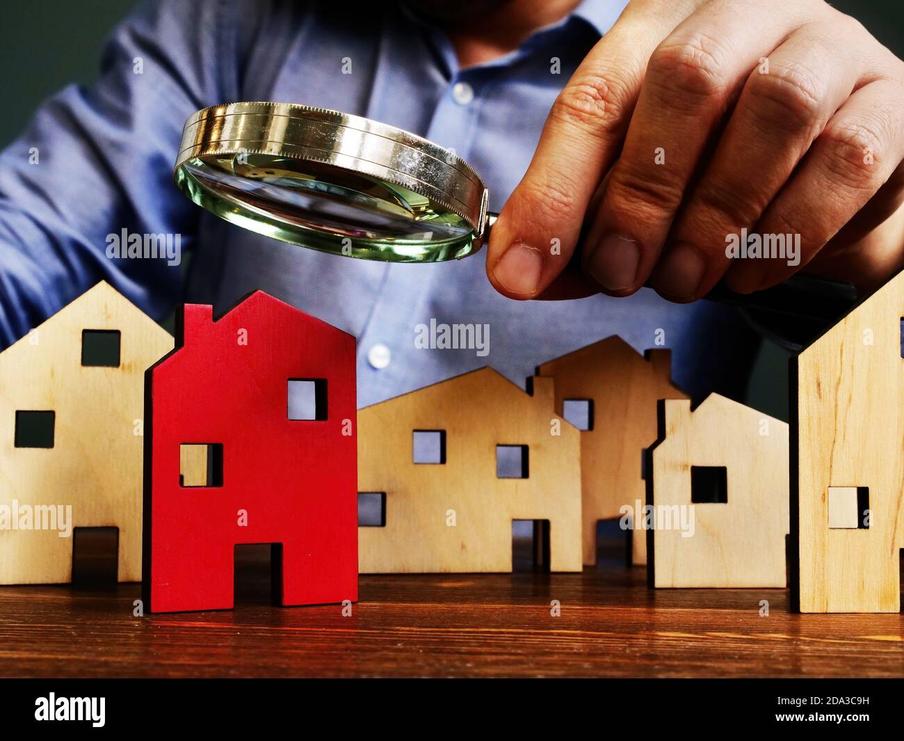 Immobilienbewertung. Ein Mann verwendet eine Lupe, um ein Haus zu wählen. Stockfoto