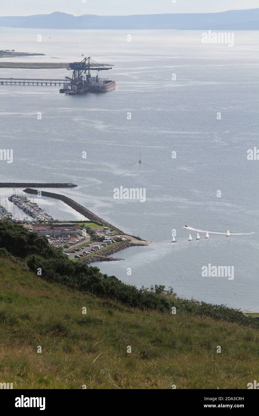 Hunterston Deep Water Harbor, North Ayrshire, Schottland, Großbritannien.Hunterston Terminal, in North Ayrshire, Schottland, war ein Eisenerz- und Kohleumschlaghafen in Fairlie am Firth of Clyde, der von Clydeport betrieben wurde und 2003 von der Peel Group übernommen wurde. Im Vordergrund befindet sich Largs Marina mit einigen kleinen Segeljingies, die die Marina verließen Stockfoto