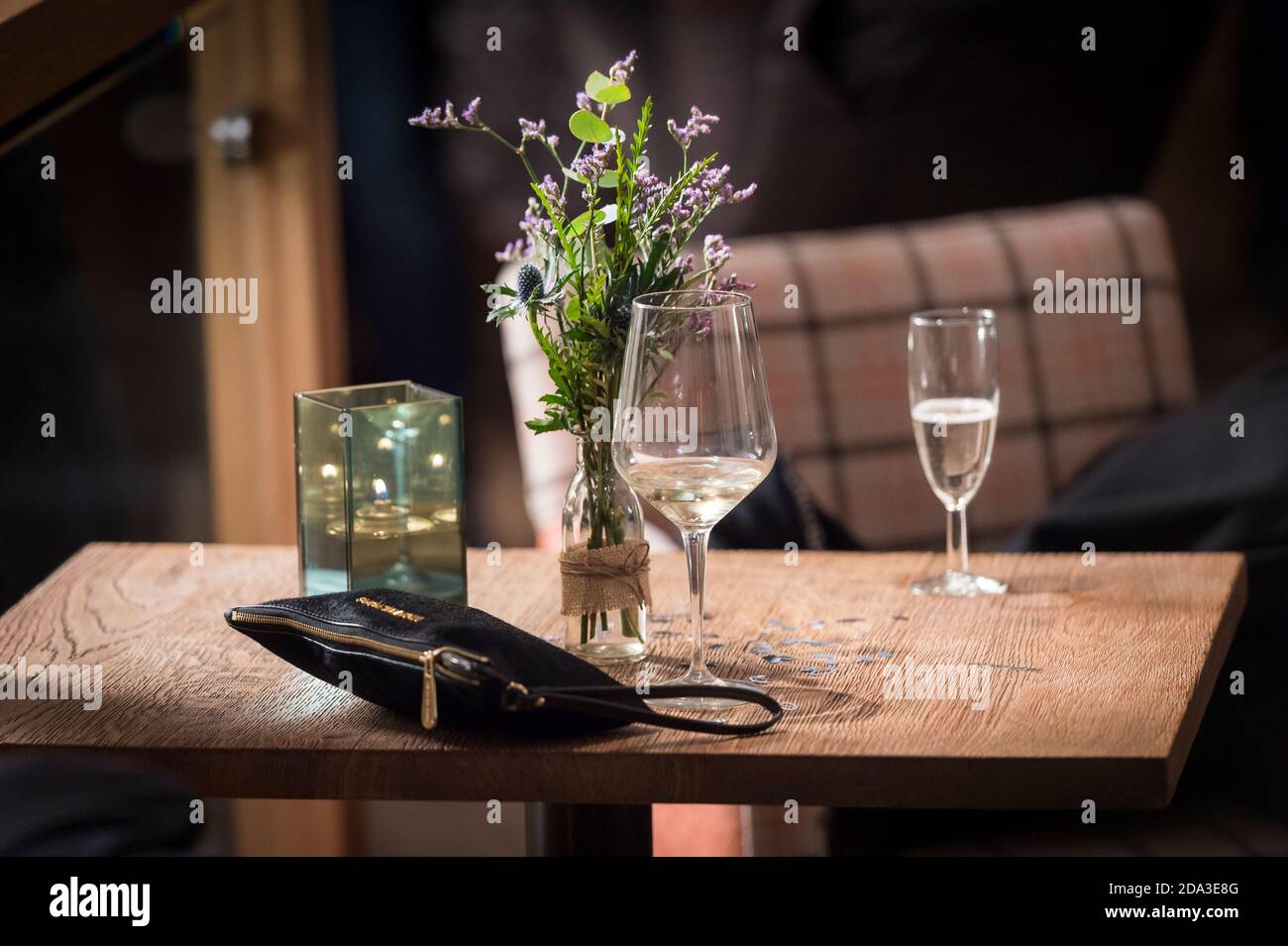 Bei einer Abendveranstaltung wurden Gläser Wein und eine Damenhandtasche auf einem Tisch zurückgelassen. Stockfoto