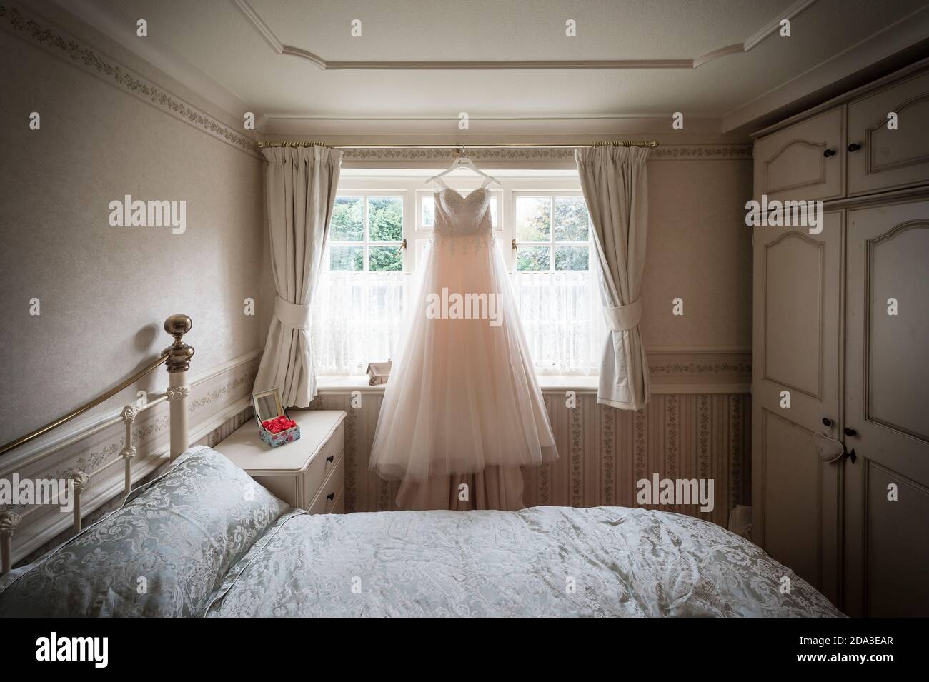 Brautkleid hängt an einem Schlafzimmerfenster. Stockfoto