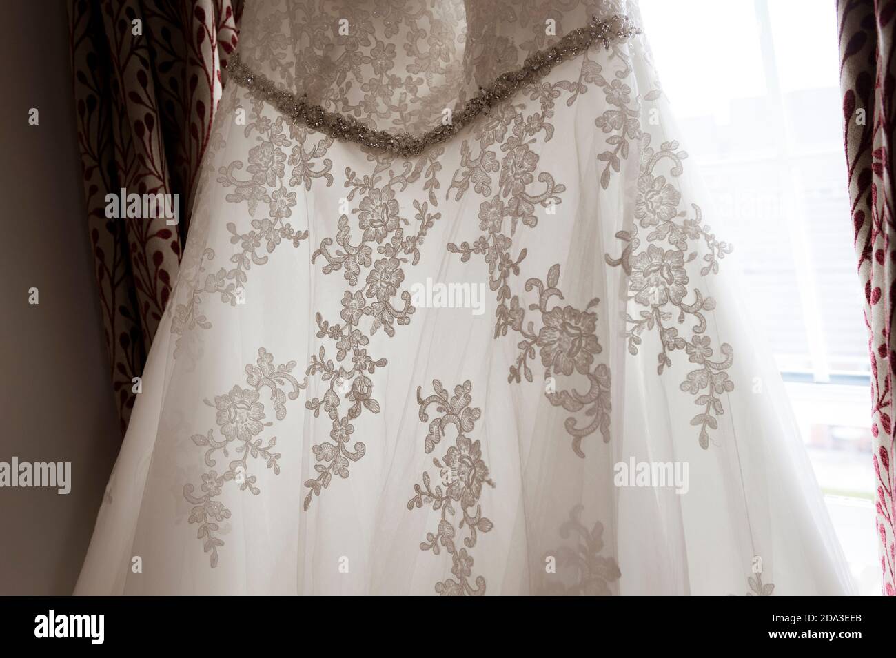 Brautkleid hängt an einem Schlafzimmerfenster. Stockfoto