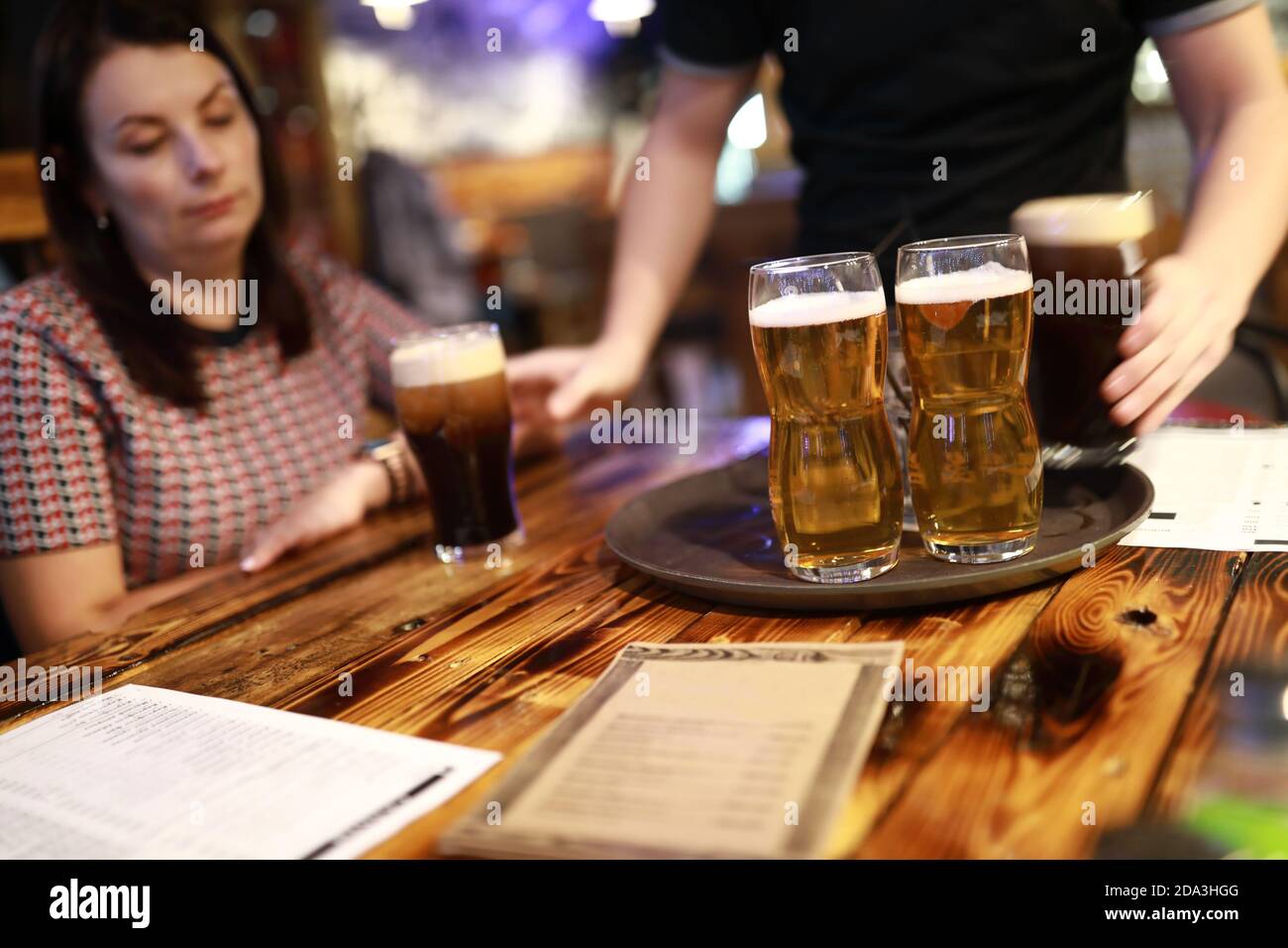 Der Kellner brachte den Gästen im Pub Gläser Bier Stockfoto