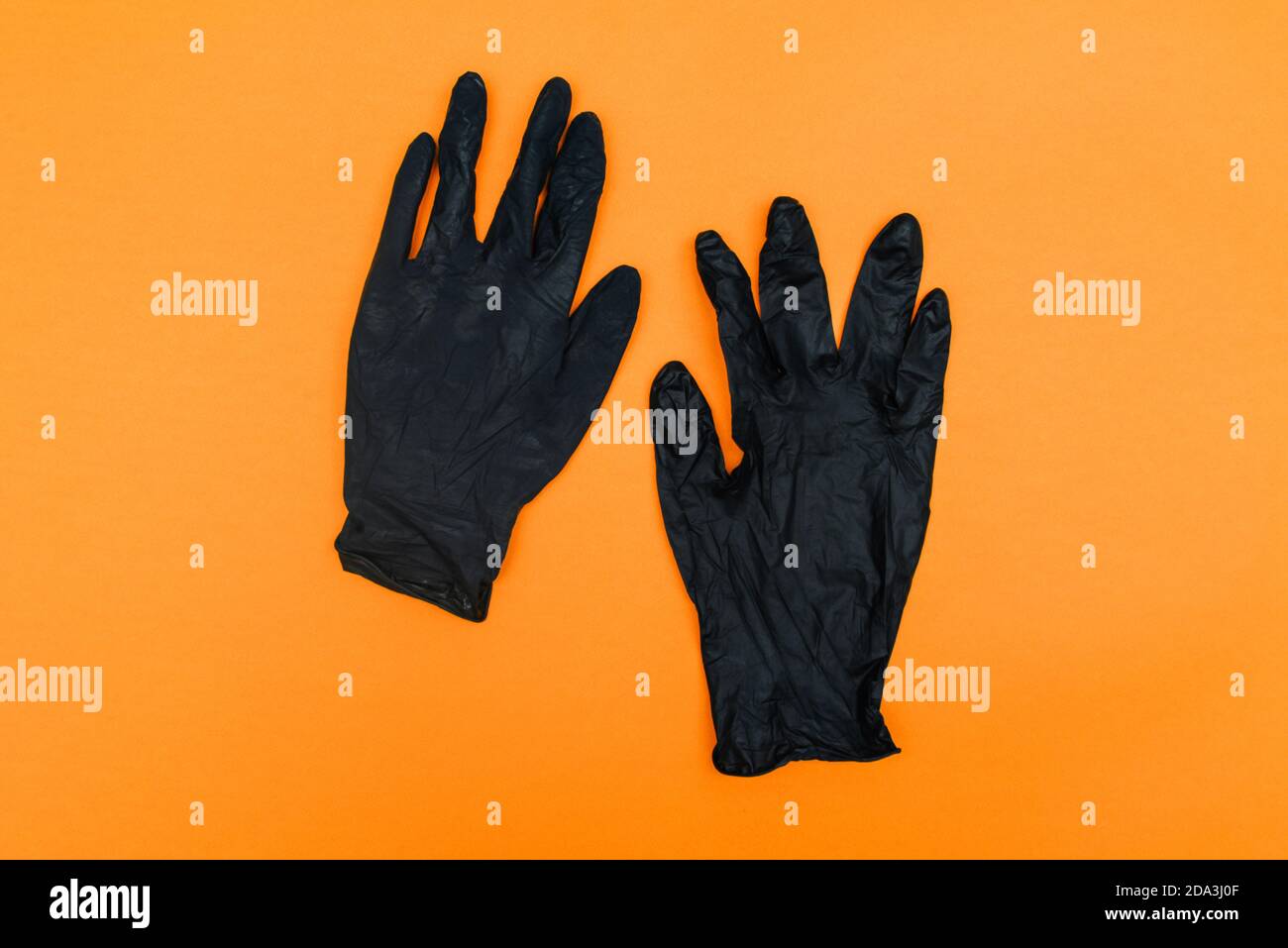 Schwarze Einweghandschuhe isoliert auf orangefarbenem Hintergrund. Handschutz vor Coronavirus, Hygiene. Draufsicht, flach liegend Stockfoto