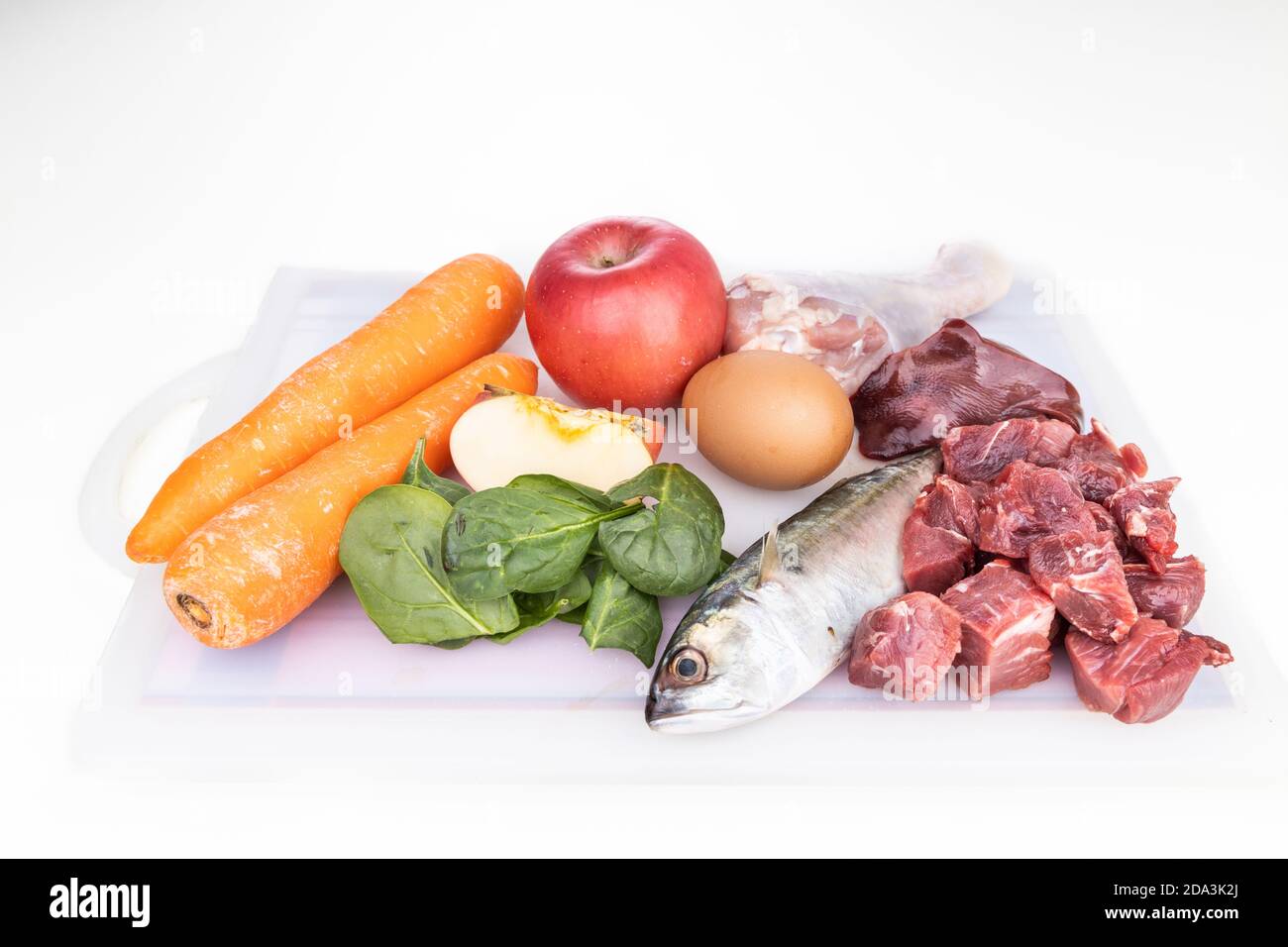 Zutaten von Barf Rohkost Rezept für Hunde bestehend aus Fleisch, Organe, Fisch, Eier und Gemüse auf Schneidebrett Stockfoto