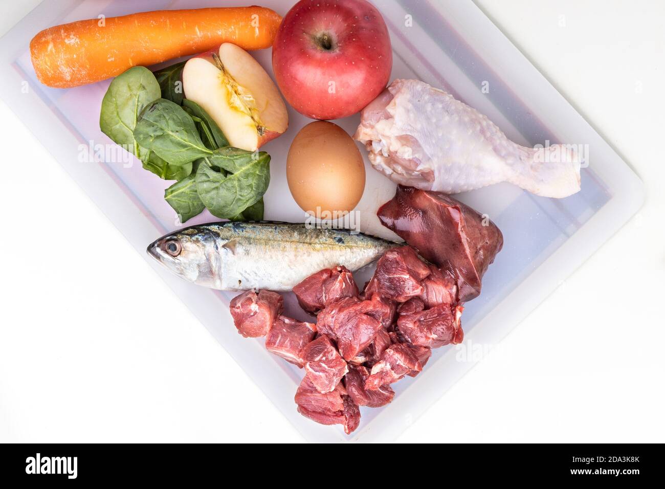 Overhead-Ansicht der Zutaten von Barf Rohkost Rezept für Hunde bestehend aus Fleisch, Organe, Fisch, Eier und Gemüse auf Schneidebrett Stockfoto