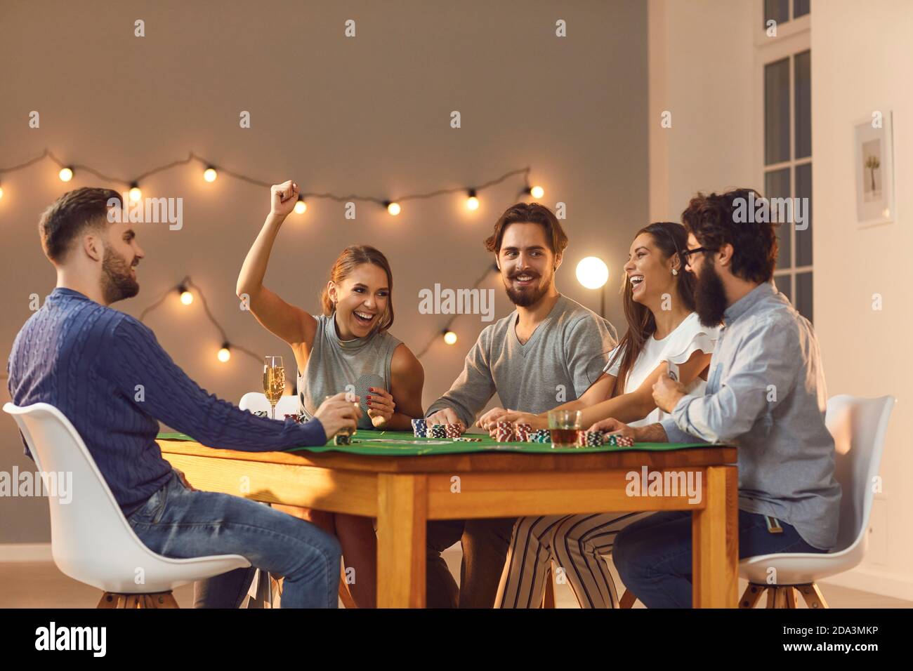 Lächelnde Freunde sitzen und spielen Poker spielen zu Hause Stockfoto