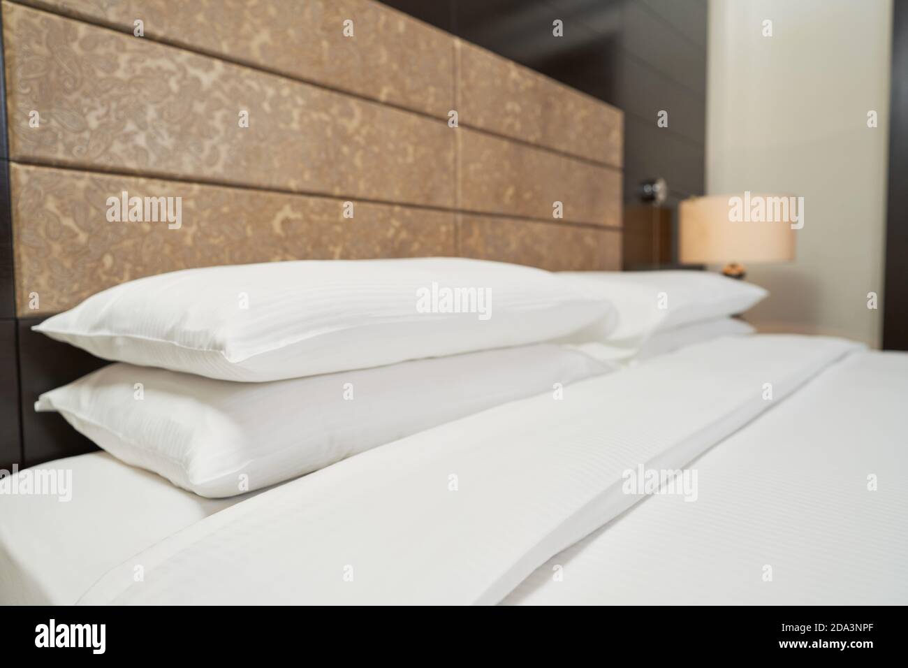 Nahaufnahme von sauberen weißen Kissen auf einem großen Bett in einer Hotelsuite. Interior Design Konzept Stockfoto