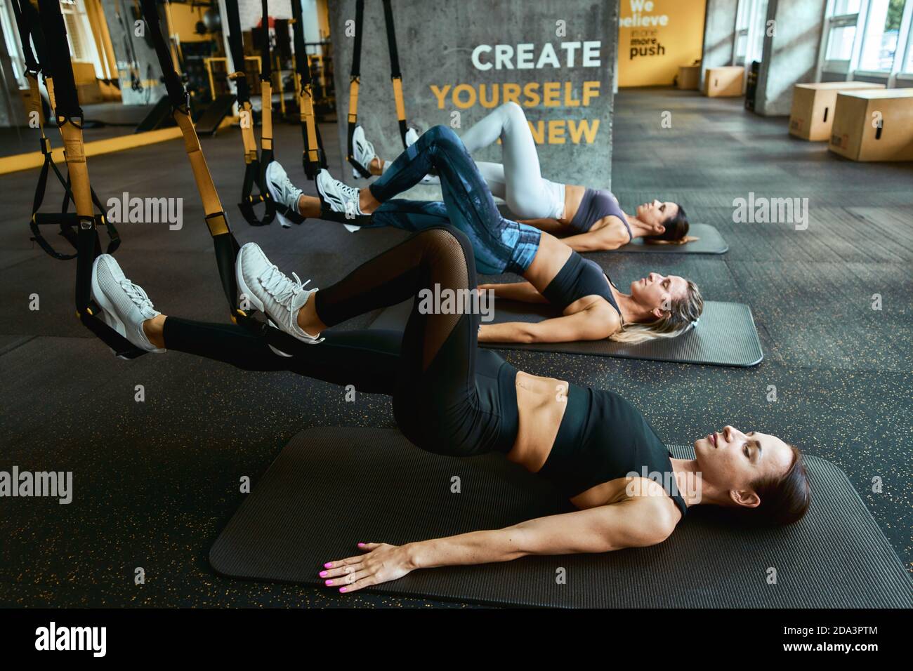 Sportliche Menschen . Drei junge sportliche Frauen trainieren mit trx-Fitnessbändern im Fitnessstudio, trainieren gemeinsam, Suspension-Trainingskonzept Stockfoto