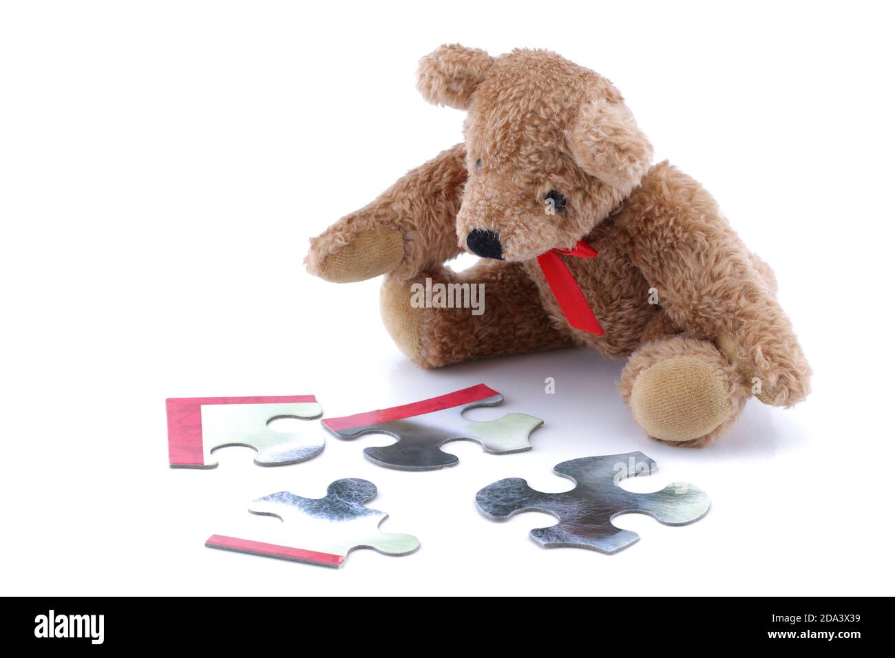 Teddybär spielt mit einem Puzzle auf weiß Stockfoto