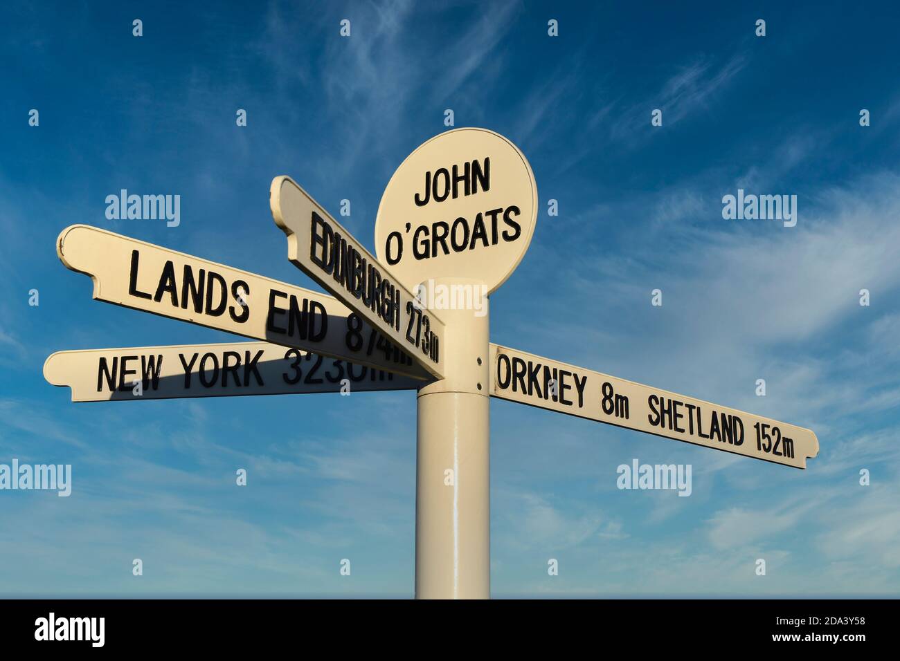 New John O'Groats Schild mit Kilometerstand nach Orkney, Shetland, Lands End, Edinburgh und New York. Isoliert gegen blauen Himmel und Licht Wolke Hintergrund Stockfoto