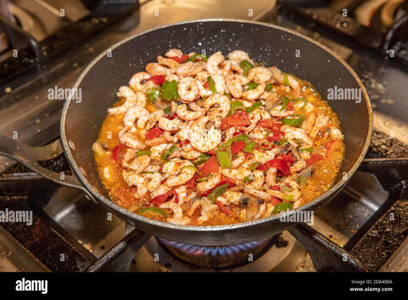 Garen Garnelen mit Austern mit Gemüse Tomaten und Grün und Mit Omelett auf einer Bratpfanne - auf einem Herd Mit Feuerhintergrund Stockfoto