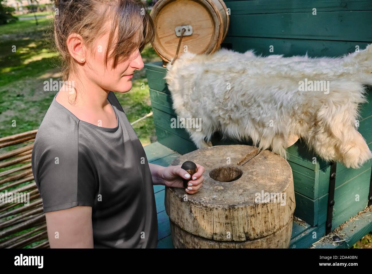 Die junge Frau mahlt Mehl mit Handmühlen. Retro Mühlstein zum Mahlen von Getreide und Mais Stockfoto