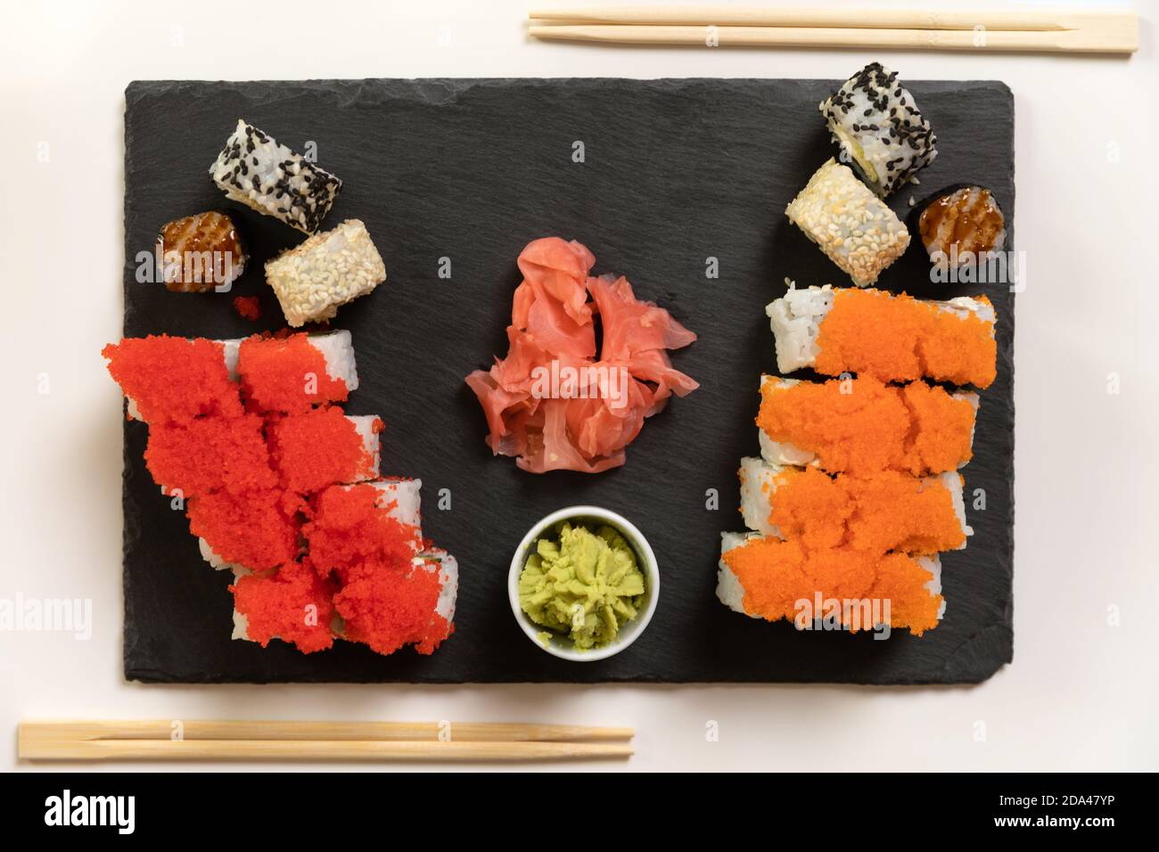 Ein Set aus farbenfrohem Sushi auf einem weißen Tisch mit Wein in einem gemütlichen Raum. Stockfoto
