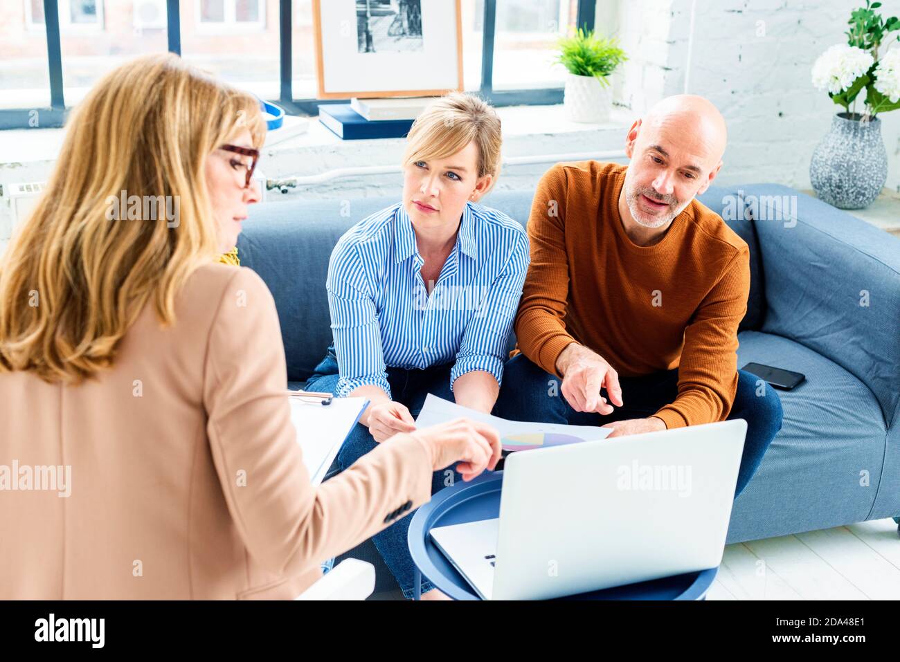 Glückliches Paar, das mit ihrem Finanzberater kommunizierte, während es zu Hause im Wohnzimmer saß. Stockfoto