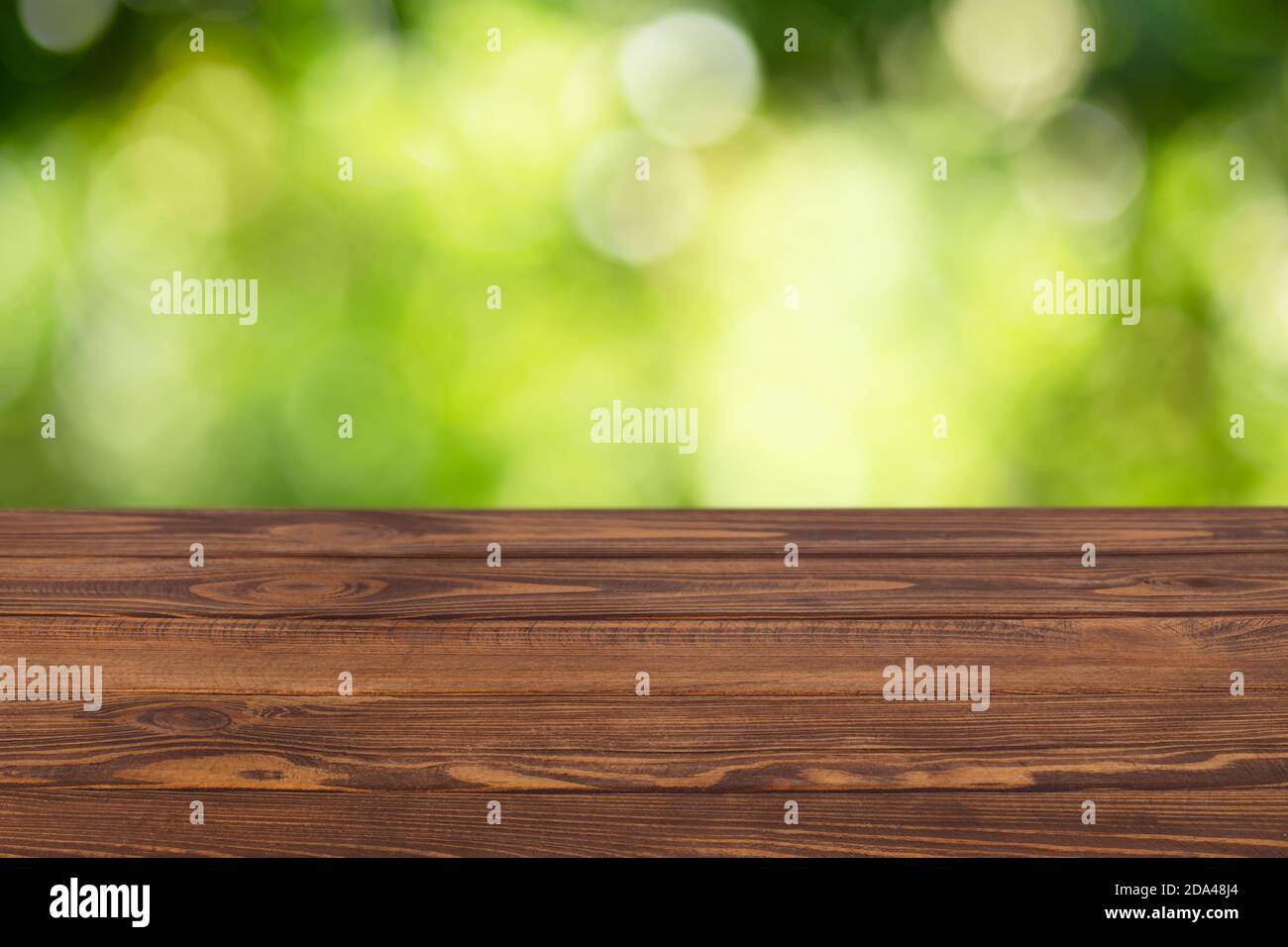 Leerer Holztisch mit verschwommenem grünen Garten Stockfoto