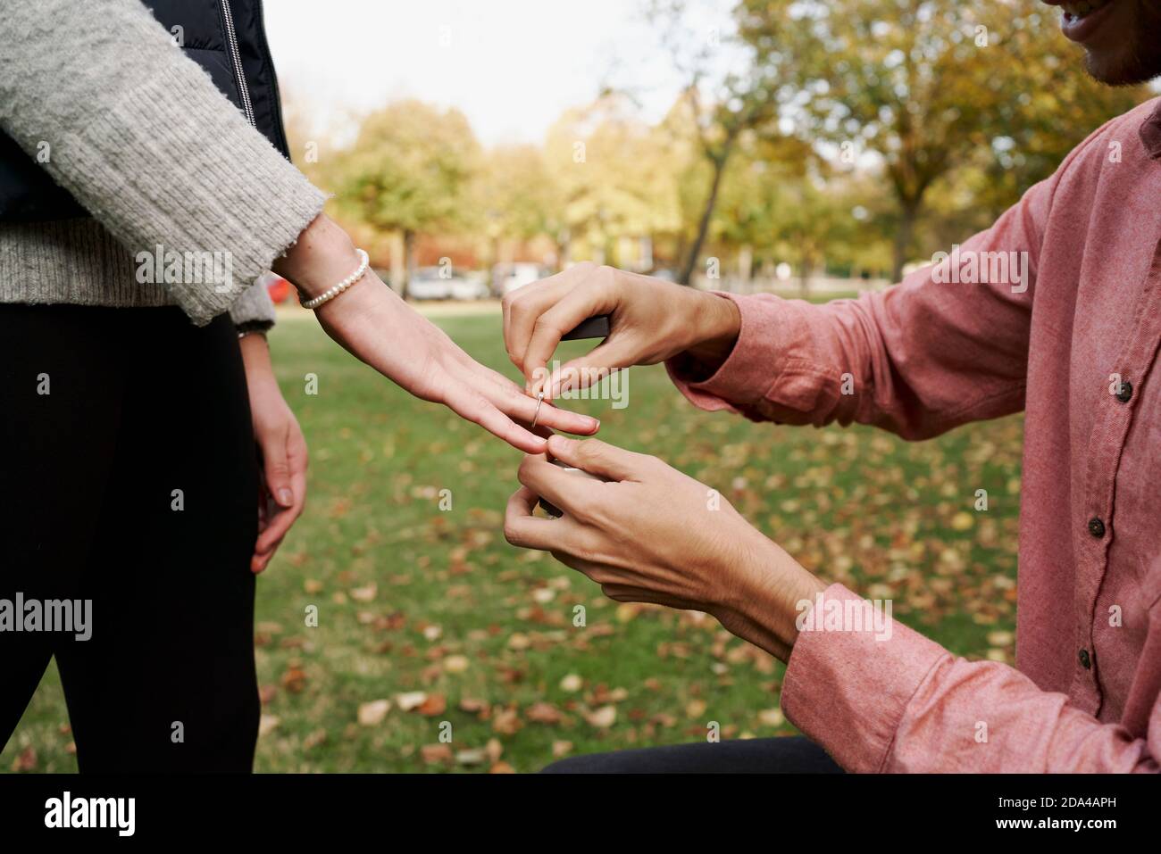 Kniender Mann, der seine Freundin mit einem Ring in einem Park heiratet. Liebeskonzept Stockfoto