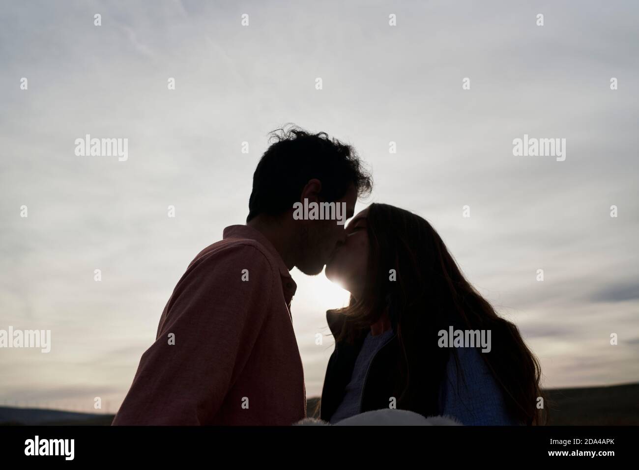 Schöne junge Paar küssen bei Sonnenuntergang in einem Park. Romantisches Konzept Stockfoto