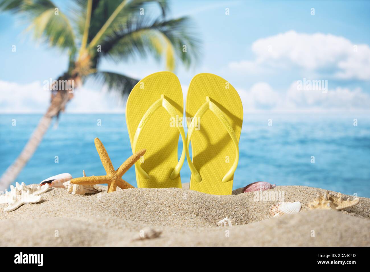 Ein Paar gelbe Pantoffeln in den Sand mit Seesternen gelegt Auf dem Meer und Palmen Hintergrund Stockfoto