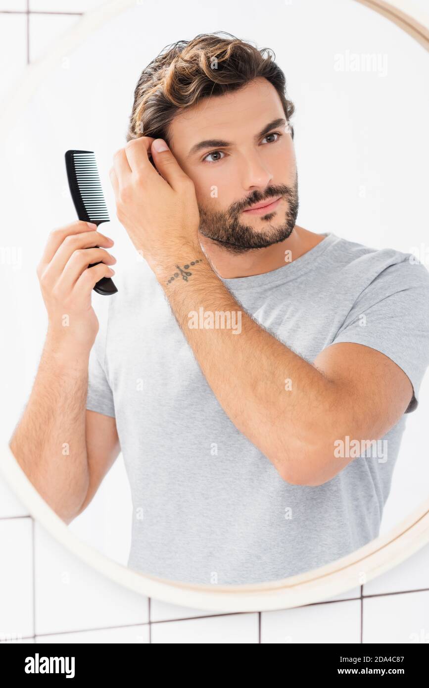 Brunette Mann Blick auf Spiegel beim Kämmen Haare im Badezimmer Stockfoto