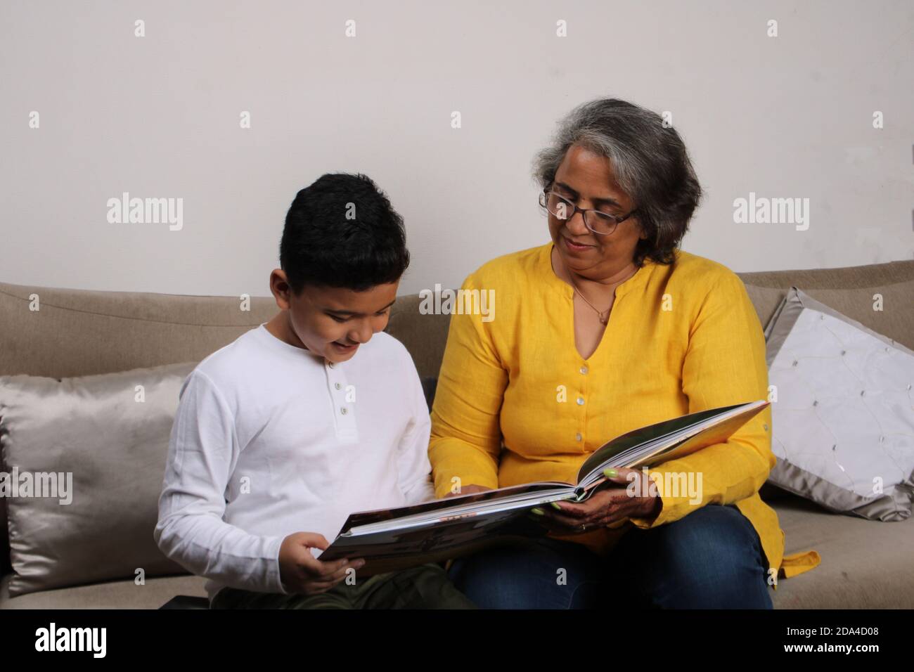 Glückliche Momente mit Oma, indische/asiatische ältere Dame verbringen gute Zeit mit ihrem Enkel Buch zusammen lesen. Stockfoto