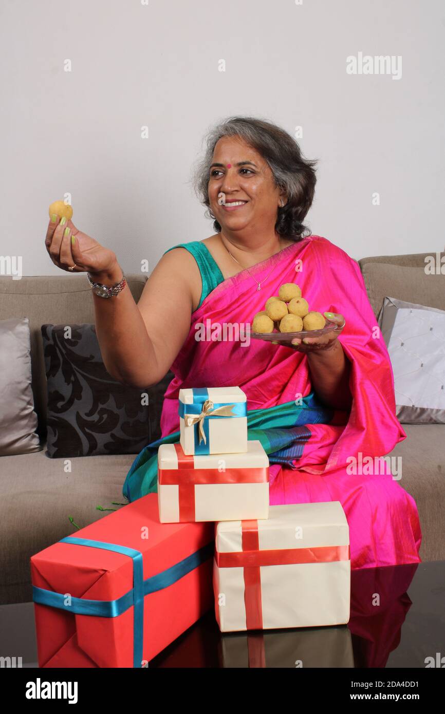 Indische Frau in Saree / Sari mit Laddu und Geschenkschachteln auf diwali / Festival. Stockfoto