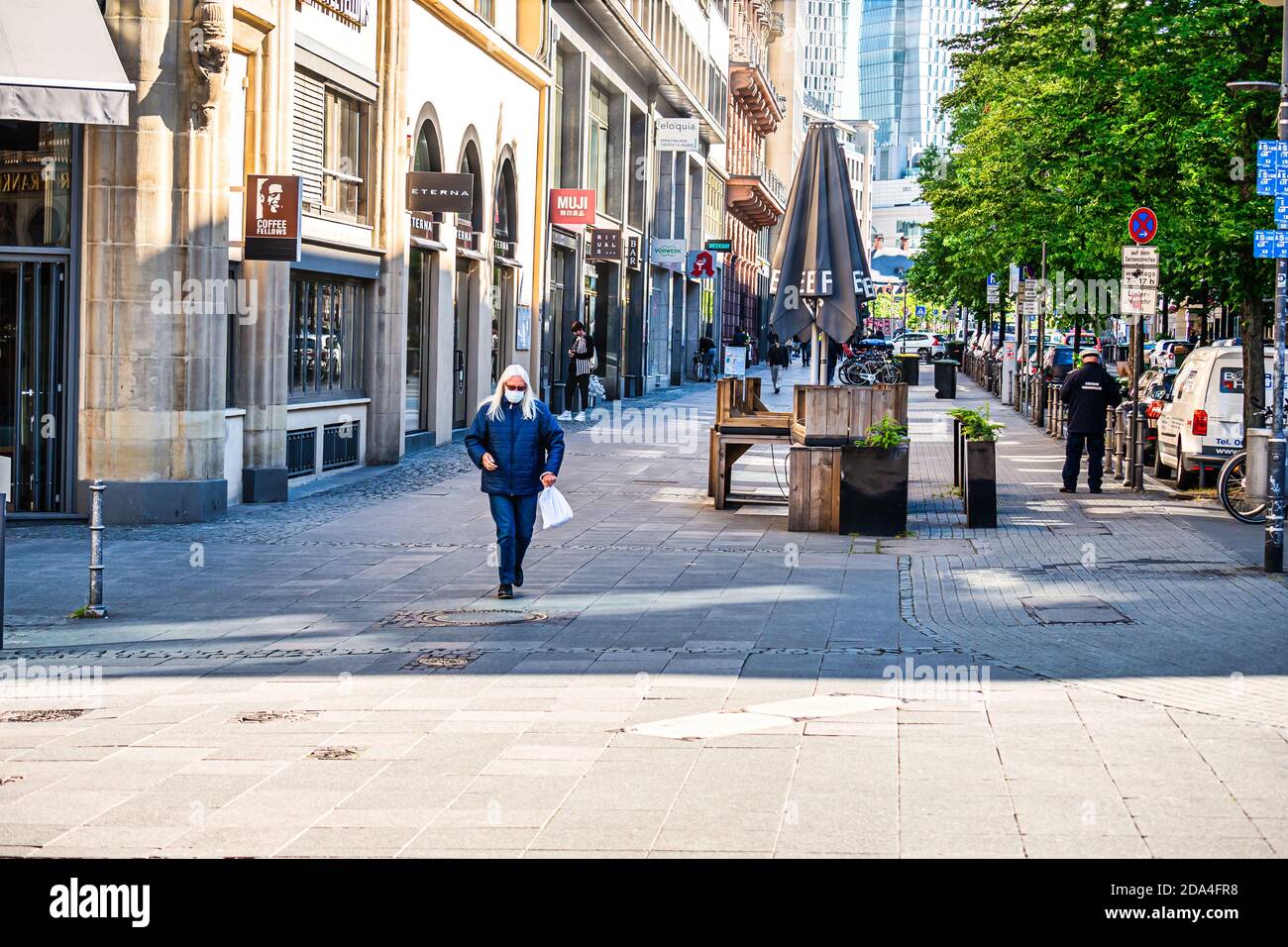 Frühjahr 2020. Frankfurt, Deutschland. Kaukasische Frau mittleren Alters, die in einer Fußgänger-Straße mit Gesichtsmaske läuft. Lange Aufnahme. Vorderansicht. Stockfoto