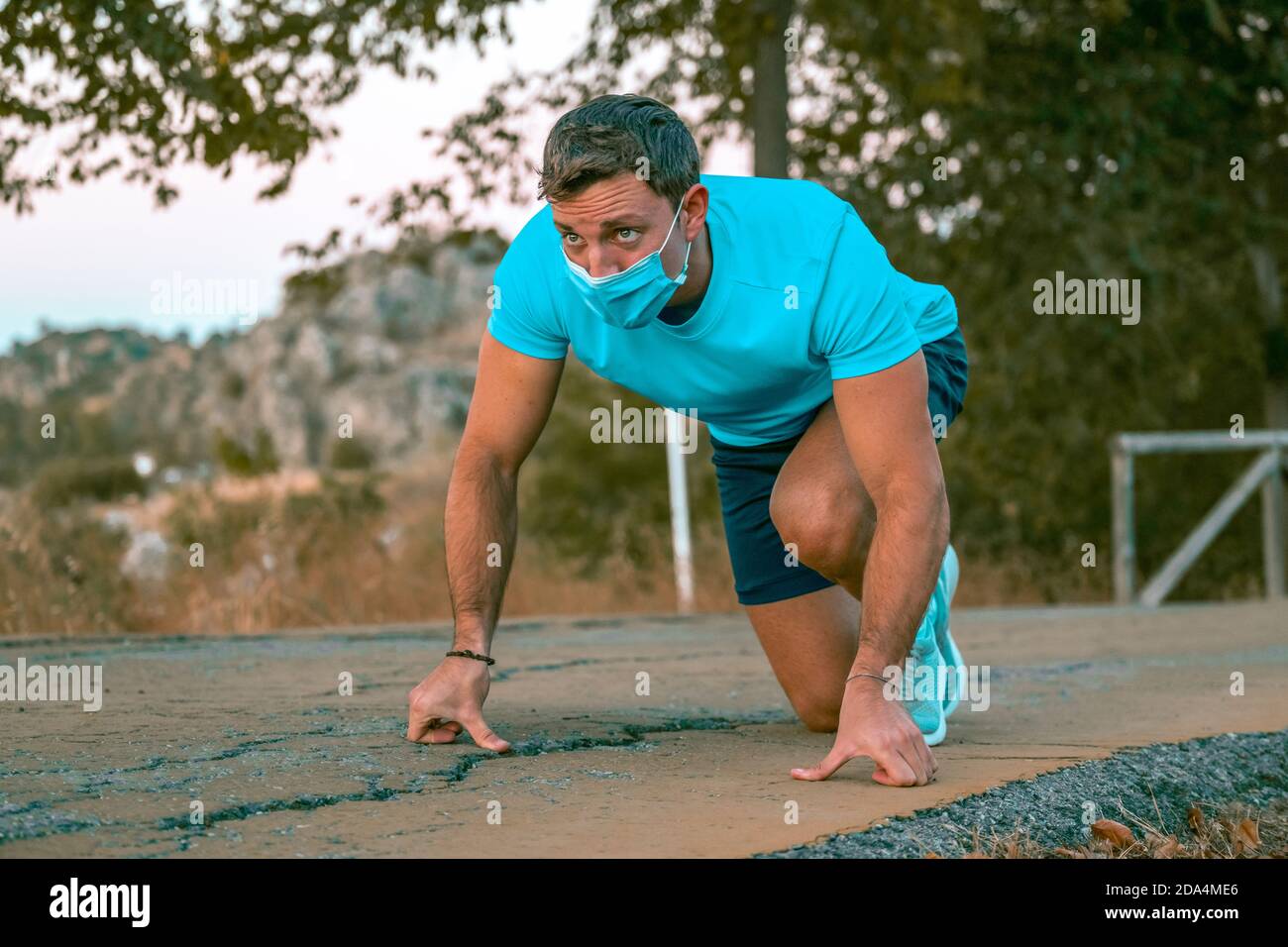 Porträt eines jungen kaukasischen Mannes mit blauem T-Shirt Vorbereitung auf einen Lauf in einem Park Stockfoto