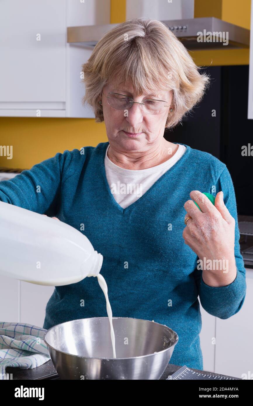 Lady in ihren späten 60ern Zutaten in ihrer Küche mischen. Stockfoto