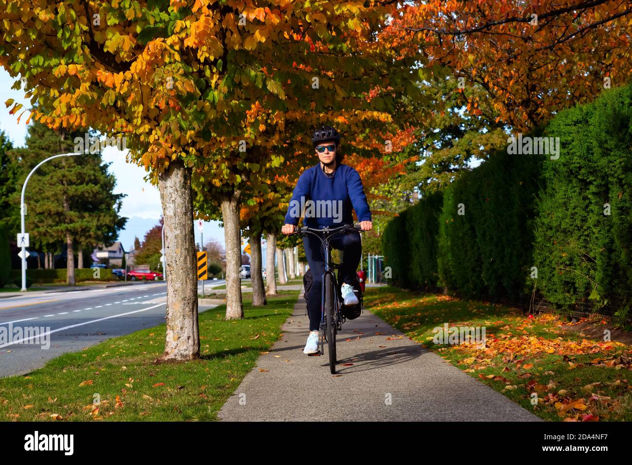 Mädchen, die ein Fahrrad auf einem Bürgersteig in einer ruhigen Nachbarschaft Stockfoto