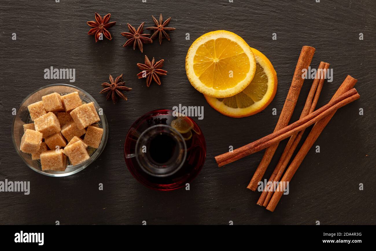 Glühwein Rezept Zutaten, Weihnachten Winter wärmende Alkohol trinken. Orange, Zimtstangen, Sternanis und Zucker auf schwarzem Stein, Draufsicht Stockfoto