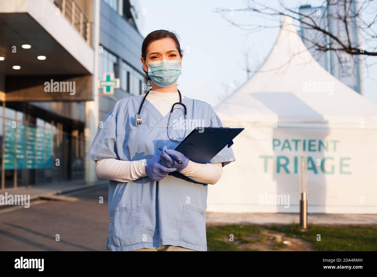 Porträt einer müden erschöpften kaukasischen NHS-Schlüsselärztin Vor Klinik oder Krankenhaus, Patient im Freien Triage Zelt, Coronavirus COVID-19 Virus Stockfoto