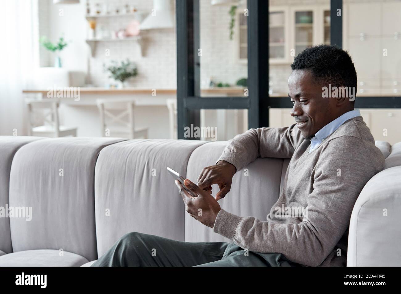 Entspannter afrikanischer Mann mit digitalen Tablet-Apps sitzen auf Couch zu Hause. Stockfoto