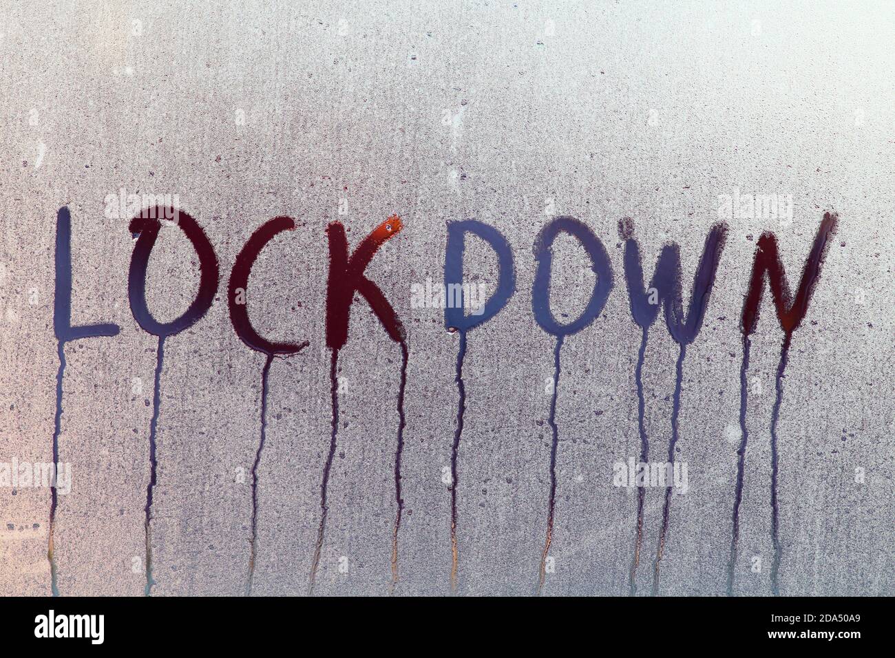 Inschrift Lockdown auf dem nebligen Fenster in Wassertropfen. Nahaufnahme des feuchten Glasfensters. Stockfoto