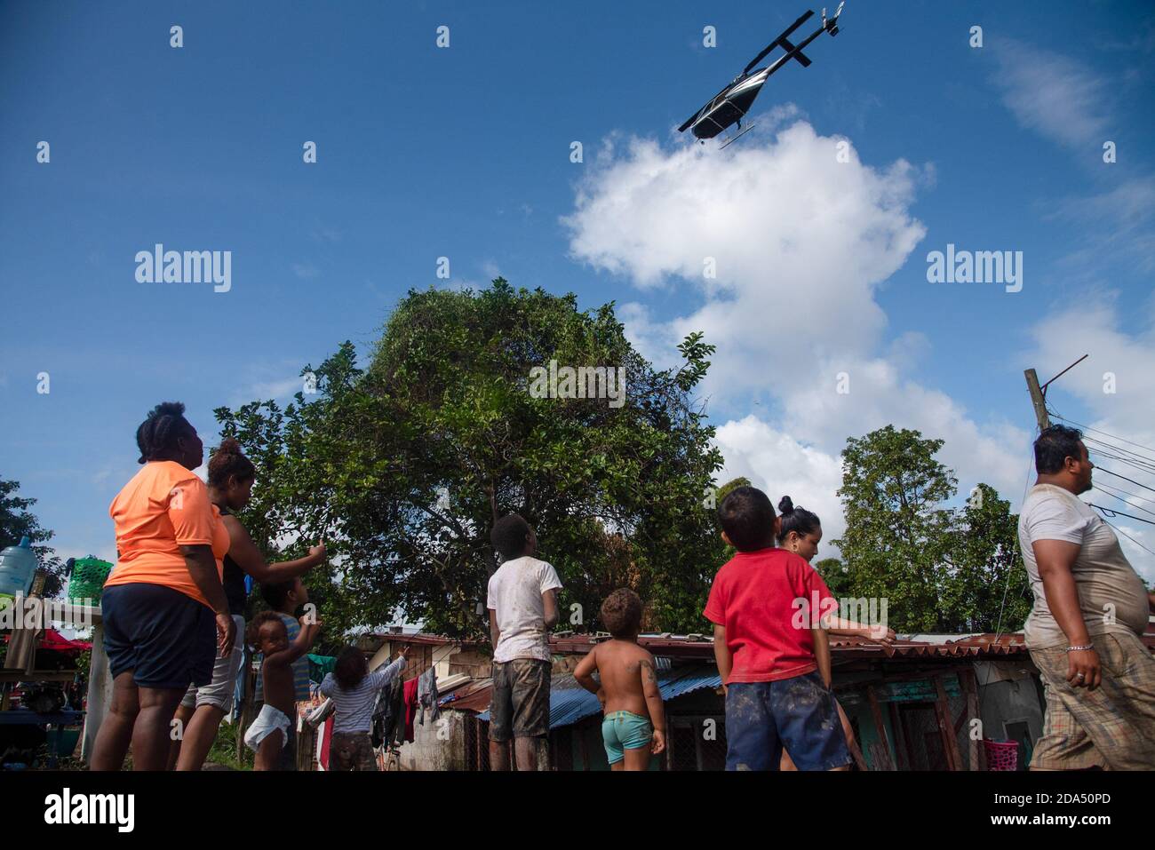 Ein Rettungshubschrauber, der über einer überschwemmten Gemeinde von La Lima, Honduras, fliegt. Ein provisorisch behelfsmäßiges Flüchtlingslager hat die mittlere und eine Spur der Hauptautobahn in San Pedro Sula, Honduras, übernommen, wo die schlimmsten Überschwemmungen durch Hurrikan Eta fast 2 Millionen Menschen getroffen haben. Der honduranischen Regierung fehlen die Ressourcen und die Logistik, um die betroffenen Menschen zu beherbergen. Stockfoto