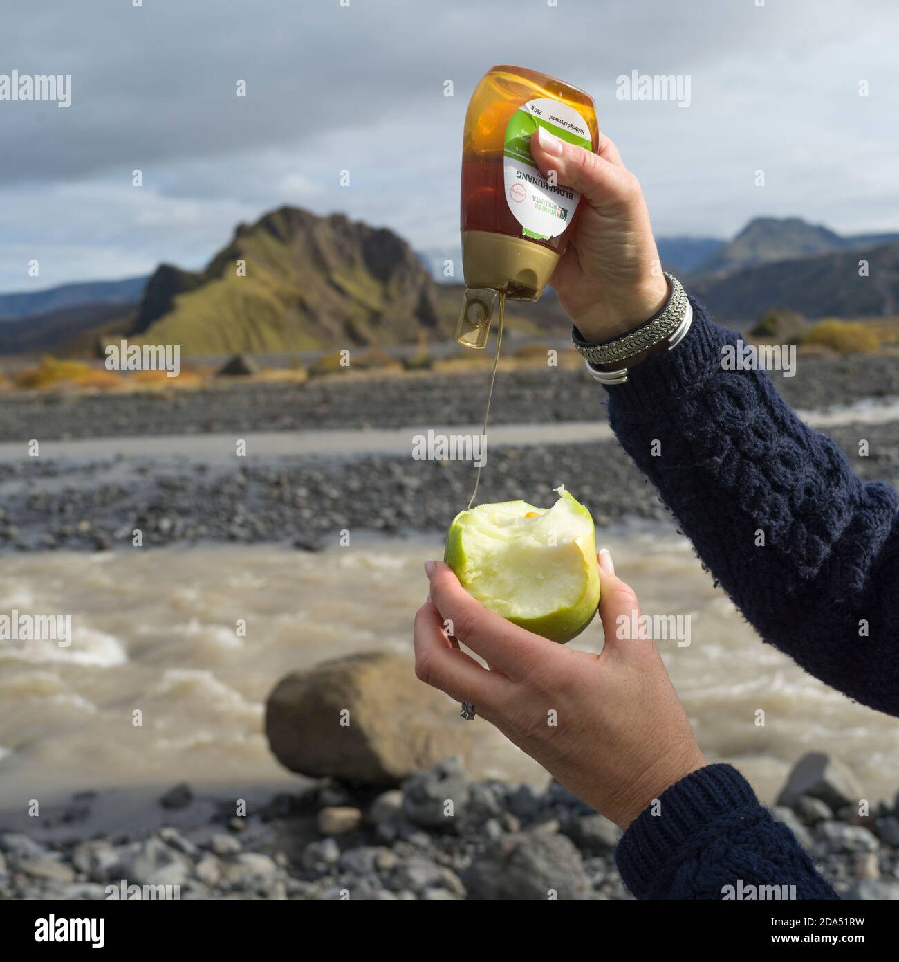 Person Gießen Honig auf einen Apfel, Rangarthing Eystra, Southern Region, Island Stockfoto