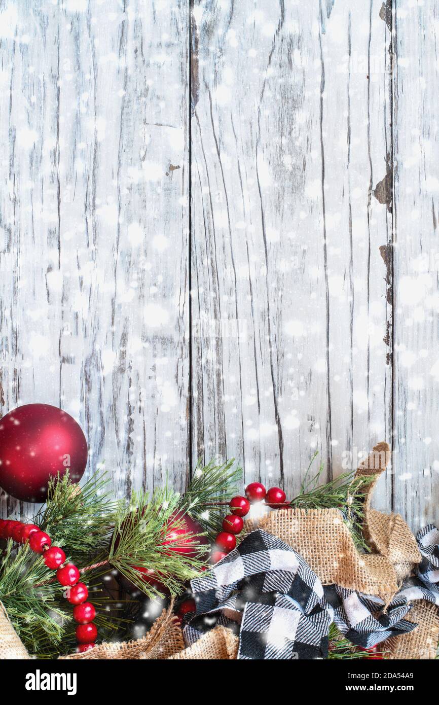 Verschneite Weihnachten Hintergrund mit Urlaub Besatz von Kiefern Äste, Ornamente, schwarz und weiß Büffelband Karo, Sackleinen und rote Perle Girlande. Stockfoto