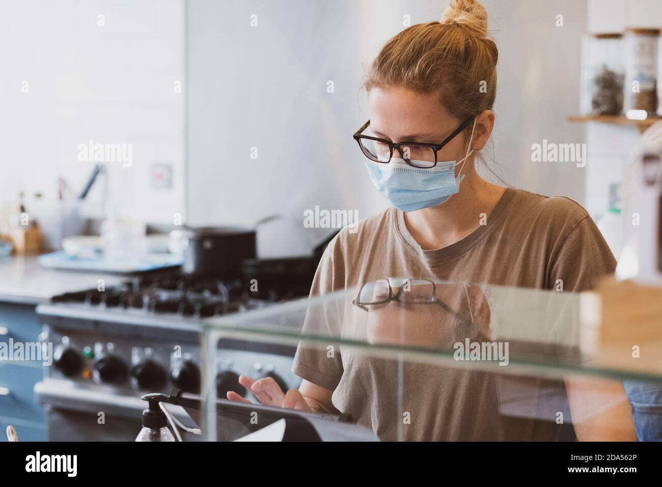 Blonde Kellnerin trägt Gesichtsmaske arbeiten in einem Café. Stockfoto