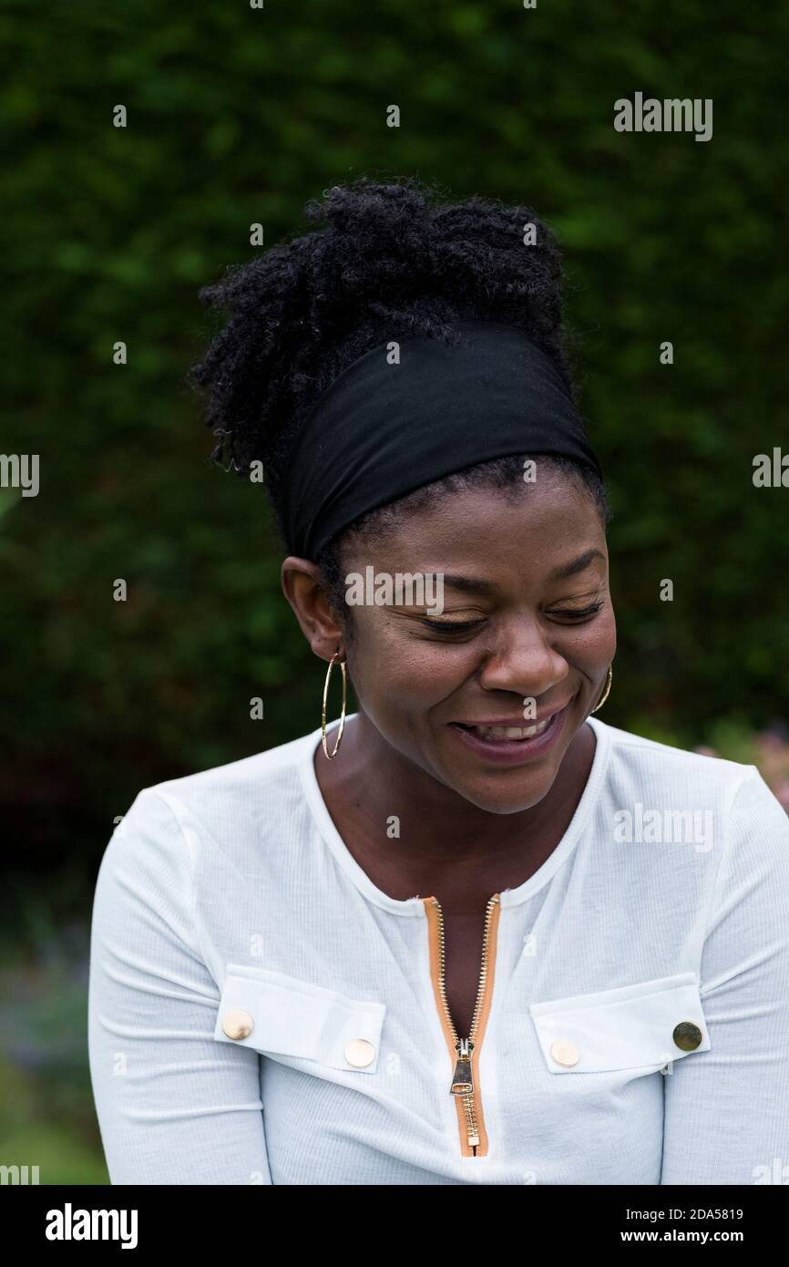 Porträt einer schwarzen Frau, die in einem Garten sitzt und während einer alternativen Therapie lächelt. Stockfoto